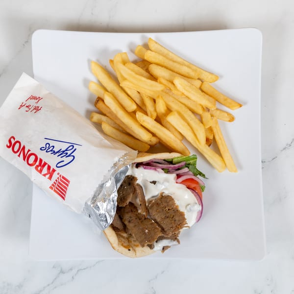 Kronos Gyros with meat, sauce, and vegetables, served with a side of golden french fries.