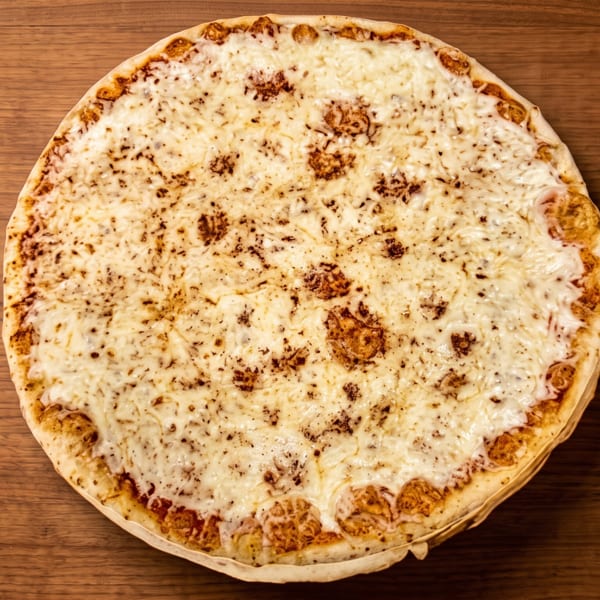 A whole cheese pizza with a golden crust and melted cheese, on a wooden table.