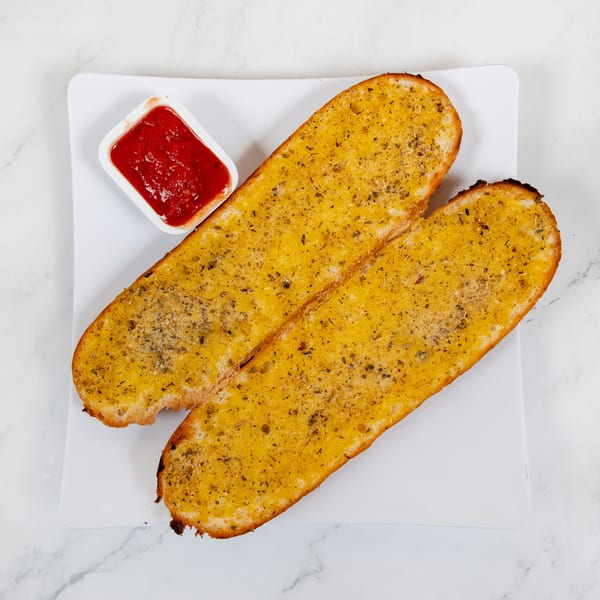 Two golden-brown garlic bread slices with herbs and a side of red marinara sauce on a white plate.