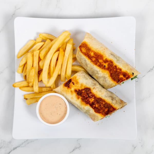 Two golden-brown wraps, french fries, and a small bowl of dipping sauce on a white plate.
