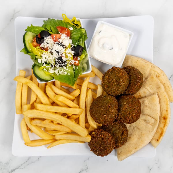 Falafel platter with fries, Greek salad, pita bread, and a side of tzatziki sauce.